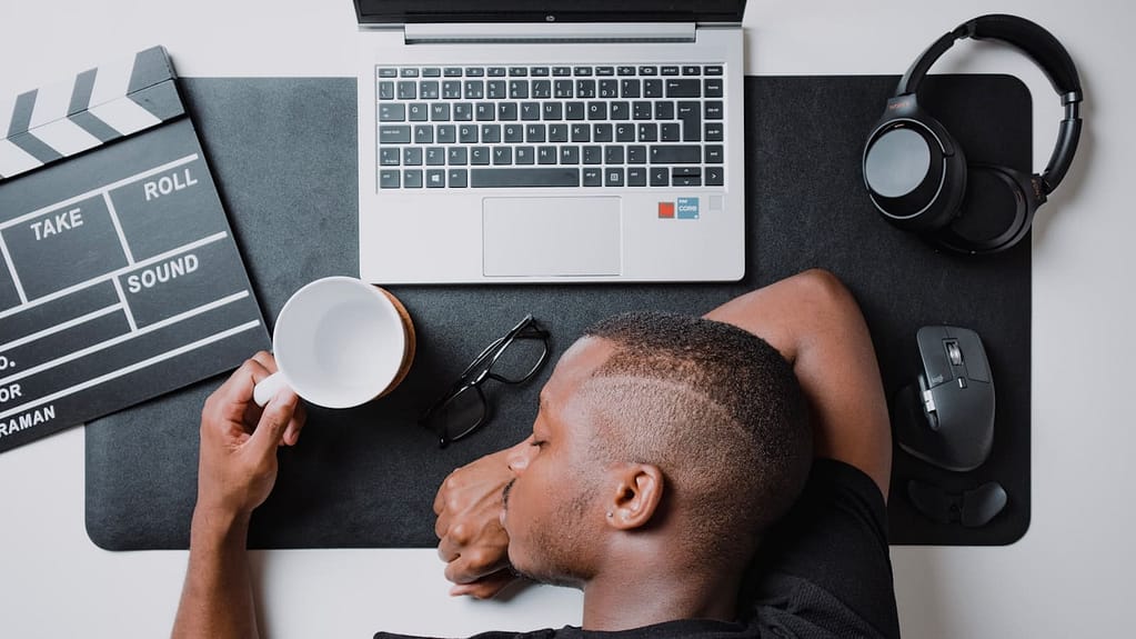 a man sitting at a desk with a laptop and headphones. Is Procrastination a Sign of ADHD? Understanding the Connection for Entrepreneurs