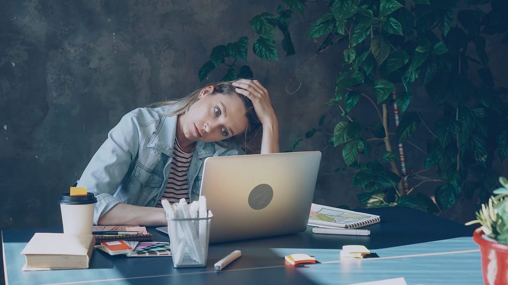 A woman appears stressed while working on laptop. overcoming adhd in business