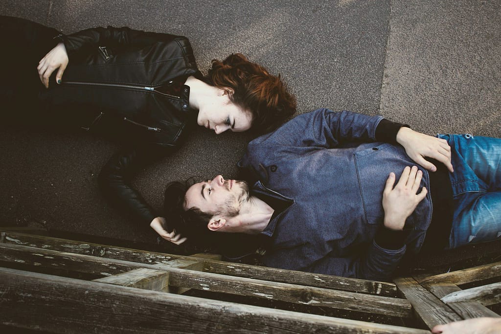 man and woman lying on gray concrete surface looking at each other - living with a partner with ADHD