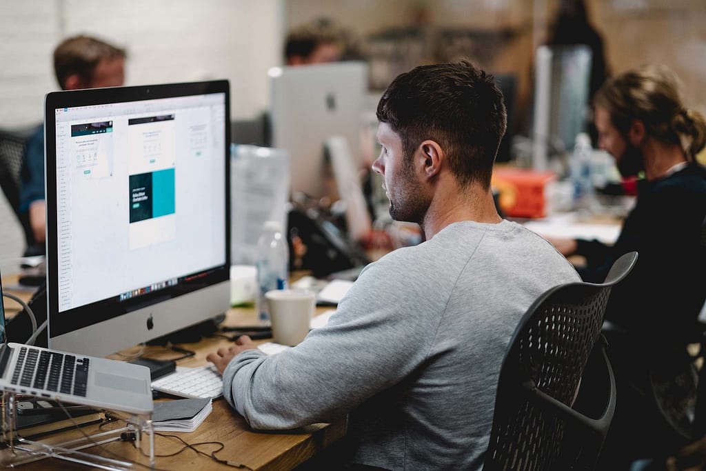 man in gray sweatshirt sitting on chair in front of iMac - ADHD Support at Work