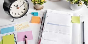 A workspace with planner, sticky notes, and clock.