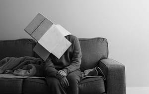 Photo by Joel Lee - Philanthropeak Coaching a person sitting on a couch with a book on their head - what adhd feels like