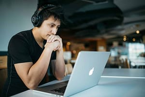 Is ADHD a Learning Disability - Philanthropeak Coaching Is ADHD a Learning Disability man wearing headphones while sitting on chair in front of MacBook - ADHD coach UK