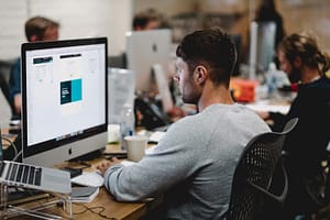 Photo by Studio Republic - Philanthropeak Coaching man in gray sweatshirt sitting on chair in front of iMac - ADHD Support at Work