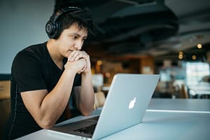 Photo by Wes Hicks - Philanthropeak Coaching man wearing headphones while sitting on chair in front of MacBook - adhd coaching online