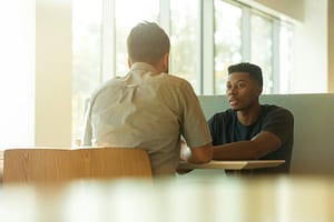 a man sitting at a table talking to another man best adhd coaching program